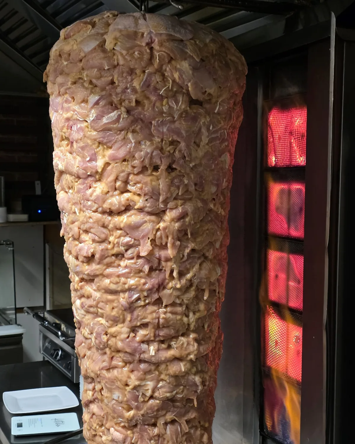 Raw meat on a spit next to a hot grill