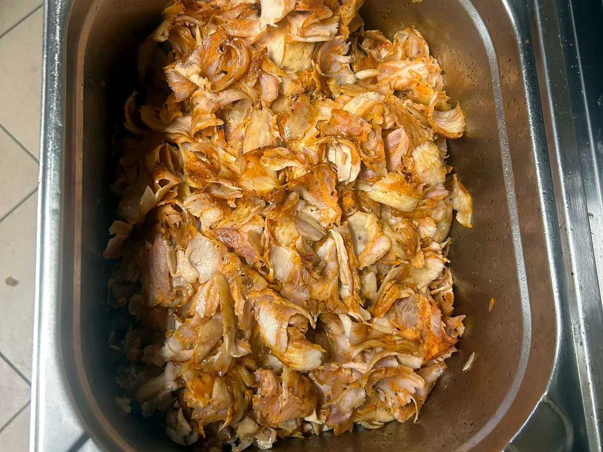 Freshly carved kebab meat in a stainless steel tray